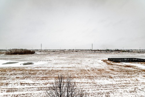 Expansive property with a field of brown ground partially covered in snow and visible tire tracks - 411 6925 199 Street Nw, Edmonton, AB - Outdoor With View