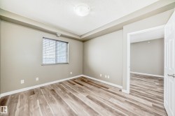 The room features wood-look flooring, light-colored walls, and a window with blinds - 