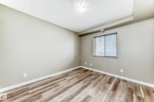 This room features light-colored walls and wood-look flooring - 411 6925 199 Street Nw, Edmonton, AB - Indoor Photo Showing Other Room