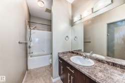 This bathroom features a vanity with a white basin sink, a dark wood cabinet, and a patterned countertop - 