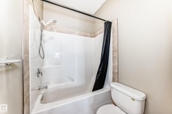 Bathroom featuring a white bathtub and shower combination with a handheld showerhead and a tiled surround - 