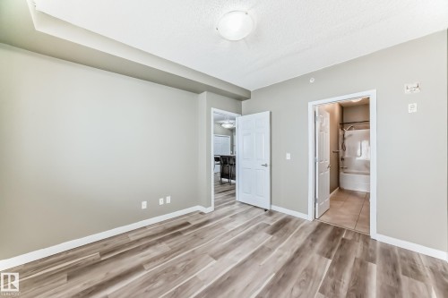 This room features wood-look flooring, light-colored walls, and a white ceiling - 411 6925 199 Street Nw, Edmonton, AB - Indoor Photo Showing Other Room