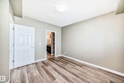 This room features wide plank flooring and light-colored walls - 411 6925 199 Street Nw, Edmonton, AB - Indoor Photo Showing Other Room