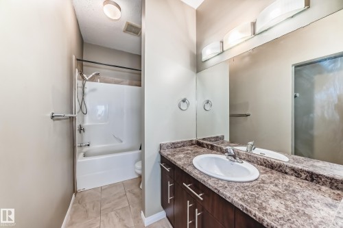 This bathroom features a vanity with a white basin sink, a dark wood cabinet, and a patterned countertop - 411 6925 199 Street Nw, Edmonton, AB - Indoor Photo Showing Bathroom