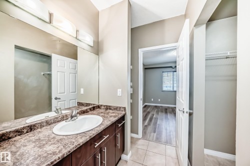 The bathroom features a vanity with a countertop and a single basin sink - 411 6925 199 Street Nw, Edmonton, AB - Indoor Photo Showing Bathroom