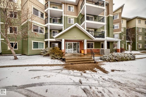 The property features a multi-story building with a covered entrance, exterior balconies, and a facade with green siding - 411 6925 199 Street Nw, Edmonton, AB - Outdoor With Balcony With Facade