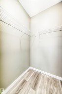 This closet features wire shelving, light-toned walls, and wood-look flooring with white baseboards - 