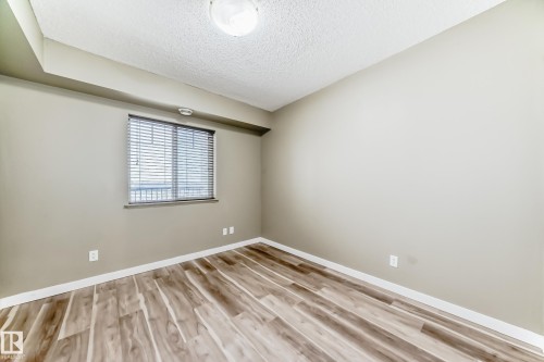 This room features light-colored walls and wood-look flooring - 411 6925 199 Street Nw, Edmonton, AB - Indoor Photo Showing Other Room