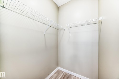 This closet features wire shelving, light-colored walls, and wood-look flooring - 411 6925 199 Street Nw, Edmonton, AB - Indoor With Storage