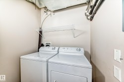 Dedicated utility area featuring a washer and dryer, with a wall-mounted wire shelf for storage - 