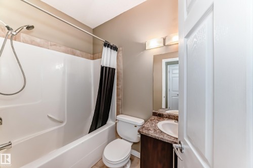 Bathroom featuring a white bathtub and shower with a tiled surround, a toilet, and a vanity with a countertop and sink - 411 6925 199 Street Nw, Edmonton, AB - Indoor Photo Showing Bathroom