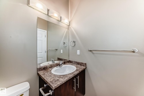 Bathroom featuring a vanity with a countertop and a white sink, a mirror, and overhead lighting - 411 6925 199 Street Nw, Edmonton, AB - Indoor Photo Showing Bathroom