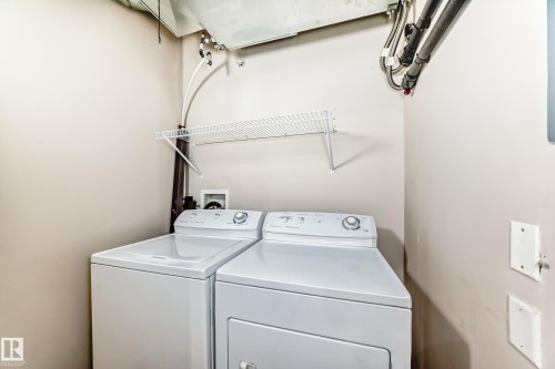 Dedicated utility area featuring a washer and dryer, with a wall-mounted wire shelf for storage - 411 6925 199 Street Nw, Edmonton, AB - Indoor Photo Showing Laundry Room