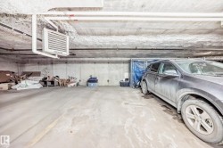 Spacious parking area with concrete flooring, exposed overhead piping, and a wall-mounted heating unit - 