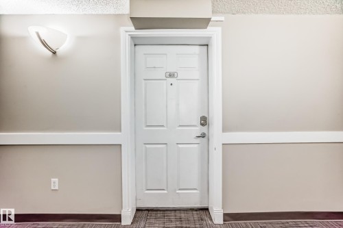 Entry door with panel details and silver-toned hardware - 411 6925 199 Street Nw, Edmonton, AB - Indoor Photo Showing Other Room