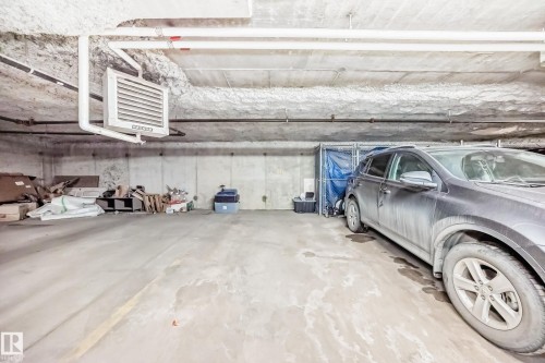Spacious parking area with concrete flooring, exposed overhead piping, and a wall-mounted heating unit - 411 6925 199 Street Nw, Edmonton, AB - Indoor Photo Showing Garage