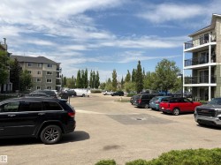 Paved parking area surrounded by multi-story residential buildings featuring exterior balconies with dark railings - 