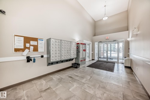 The property features a spacious lobby with tiled flooring, a high ceiling, and an array of mailboxes for convenience - 411 6925 199 Street Nw, Edmonton, AB - Indoor Photo Showing Other Room