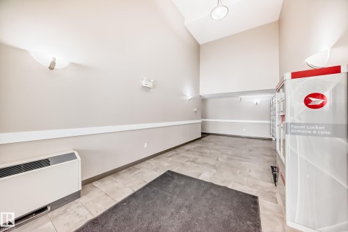 Spacious entryway featuring a high vaulted ceiling, light-toned walls, and tiled flooring - 411 6925 199 Street Nw, Edmonton, AB - Indoor Photo Showing Other Room