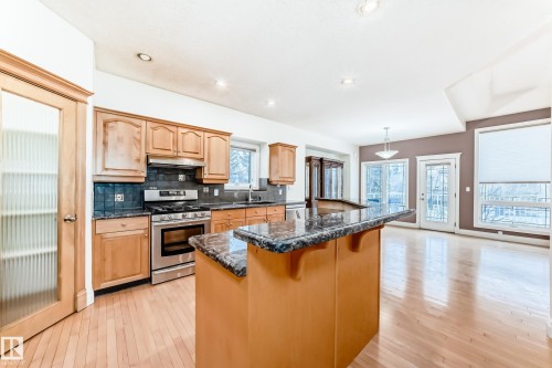 Kitchen with stainless steel appliances, pendant lighting, light wood-type flooring, dark stone countertops, and a kitchen breakfast bar - 1605 Haswell Court, Edmonton, AB - Indoor Photo Showing Kitchen