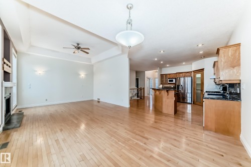 Unfurnished living room with a fireplace, light wood-style flooring, and ceiling fan - 1605 Haswell Court, Edmonton, AB - Indoor With Fireplace