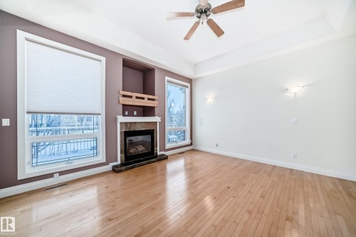 Unfurnished living room with ceiling fan, a tiled fireplace, a tray ceiling, and light wood-style floors - 1605 Haswell Court, Edmonton, AB - Indoor Photo Showing Living Room With Fireplace