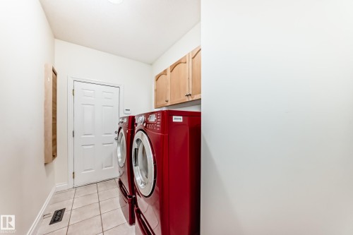 Laundry room featuring light tile patterned flooring, separate washer and dryer, and cabinet space - 1605 Haswell Court, Edmonton, AB - Indoor Photo Showing Laundry Room