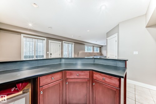 Kitchen featuring bold wood finish cabinetry, light tile patterned floors, dark countertops, and recessed lighting - 1605 Haswell Court, Edmonton, AB - Indoor Photo Showing Kitchen
