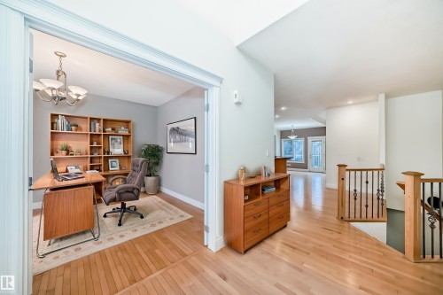 The property features a versatile office space with a built-in wooden bookshelf, light gray walls, and a chandelier - 1605 Haswell Court, Edmonton, AB - Indoor Photo Showing Office