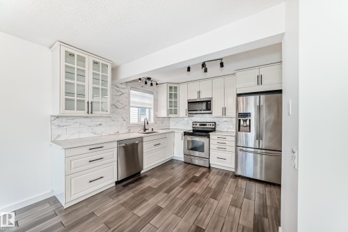 Kitchen with stainless steel appliances, white cabinets, wood tiled floors, and glass fronted cabinets - 4008 37 Avenue, Edmonton, AB - Indoor Photo Showing Kitchen