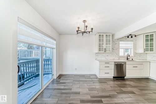 Kitchen featuring white cabinets, tasteful backsplash, wood tiled floors, dishwasher, and hanging lights - 4008 37 Avenue, Edmonton, AB - Indoor