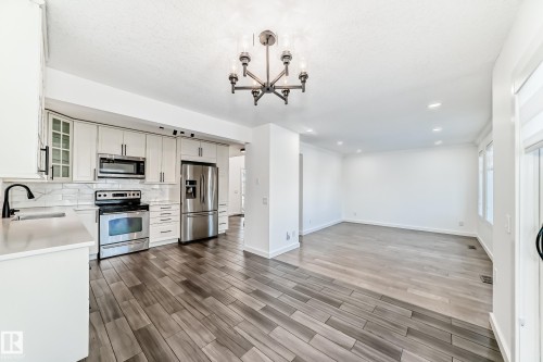 Kitchen with stainless steel appliances, wood tiled floors, open floor plan, glass insert cabinets, and tasteful backsplash - 4008 37 Avenue, Edmonton, AB - Indoor Photo Showing Kitchen