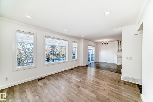 Unfurnished living room with light wood-style floors, hanging lights, and ornamental molding - 4008 37 Avenue, Edmonton, AB - Indoor