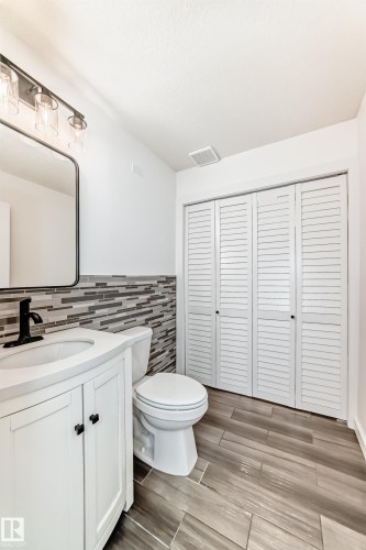 Half bath with vanity, a closet, tile walls, wood finish floors, and wainscoting - 4008 37 Avenue, Edmonton, AB - Indoor Photo Showing Bathroom