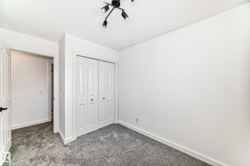 Unfurnished bedroom featuring dark colored carpet, a textured ceiling, and a closet - 4008 37 Avenue, Edmonton, AB - Indoor Photo Showing Other Room