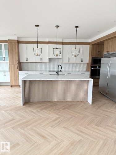 Bright kitchen featuring a waterfall island with slatted wood-finish detailing, light wood-finish herringbone flooring, a white subway tile backsplash, and a suite of stainless steel appliances - 53 Lilac Bay, Spruce Grove, AB - Indoor Photo Showing Kitchen