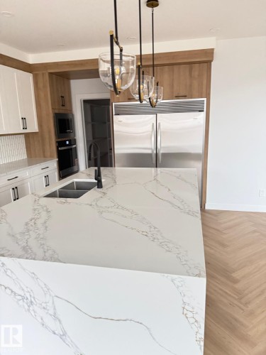 Kitchen island with waterfall countertop featuring white quartz with grey and gold veining - 53 Lilac Bay, Spruce Grove, AB - Indoor Photo Showing Kitchen With Double Sink