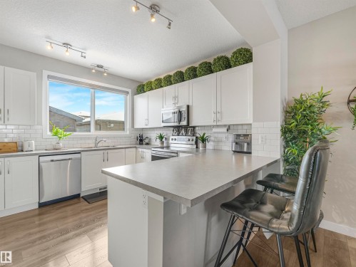 The kitchen features white cabinetry, stainless steel appliances, and light-colored countertops - 725 36 Street, Edmonton, AB - Indoor Photo Showing Kitchen With Double Sink