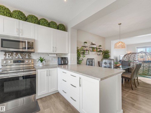 The kitchen features white cabinetry, stainless steel appliances, and light-colored countertops - 725 36 Street, Edmonton, AB - Indoor Photo Showing Kitchen
