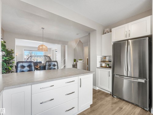 The kitchen features white cabinetry, a stainless steel refrigerator, with a light-colored countertop - 725 36 Street, Edmonton, AB - Indoor Photo Showing Kitchen