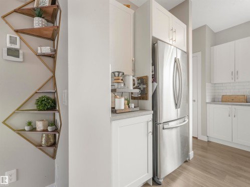 Modern kitchen featuring white cabinetry, subway tile backsplash, a stainless steel refrigerator, and wood-look flooring - 725 36 Street, Edmonton, AB - Indoor Photo Showing Kitchen