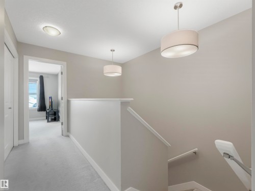 Bright hallway with light-colored carpeting, featuring white trim and modern lighting fixtures - 725 36 Street, Edmonton, AB - Indoor Photo Showing Other Room