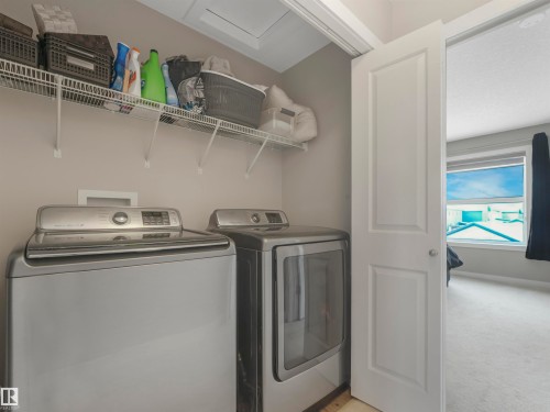 The property includes a dedicated laundry area with a washer and dryer, complemented by overhead wire shelving for storage - 725 36 Street, Edmonton, AB - Indoor Photo Showing Laundry Room