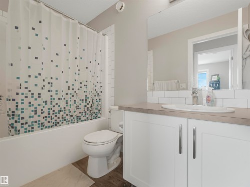 Bathroom featuring a white vanity with cabinet storage, a toilet, and a bathtub with a shower curtain - 725 36 Street, Edmonton, AB - Indoor Photo Showing Bathroom