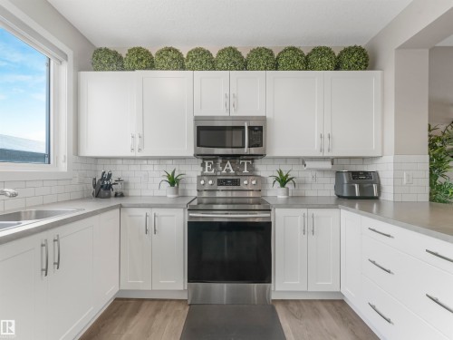 Modern kitchen featuring white cabinetry, stainless steel appliances, light-colored countertops, and a subway tile backsplash - 725 36 Street, Edmonton, AB - Indoor Photo Showing Kitchen