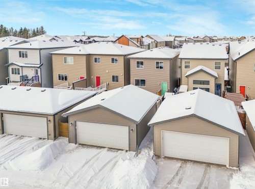 The property includes detached garages with white garage doors and a light-colored siding exterior, set against a snow-covered landscape - 725 36 Street, Edmonton, AB - Outdoor