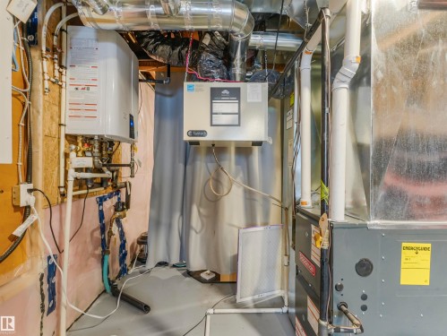 The property features a tankless water heater, a furnace, and an air handler, all visible with associated ductwork and piping - 725 36 Street, Edmonton, AB - Indoor Photo Showing Basement