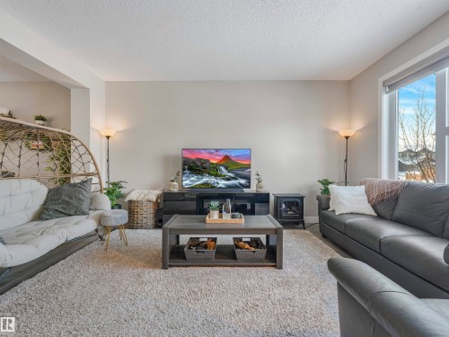 Inviting living area featuring a large window, light-colored walls, and a textured carpet - 725 36 Street, Edmonton, AB - Indoor Photo Showing Living Room