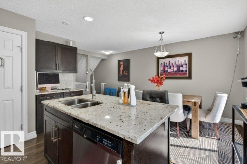 Kitchen island featuring a double basin stainless steel sink, granite countertop, and integrated dishwasher - 40 14621 121 Street, Edmonton, AB - Indoor