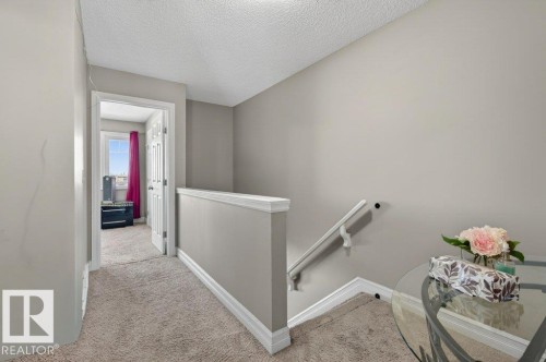 Carpeted hallway featuring a white handrail, baseboards, and a framed doorway - 40 14621 121 Street, Edmonton, AB - Indoor Photo Showing Other Room